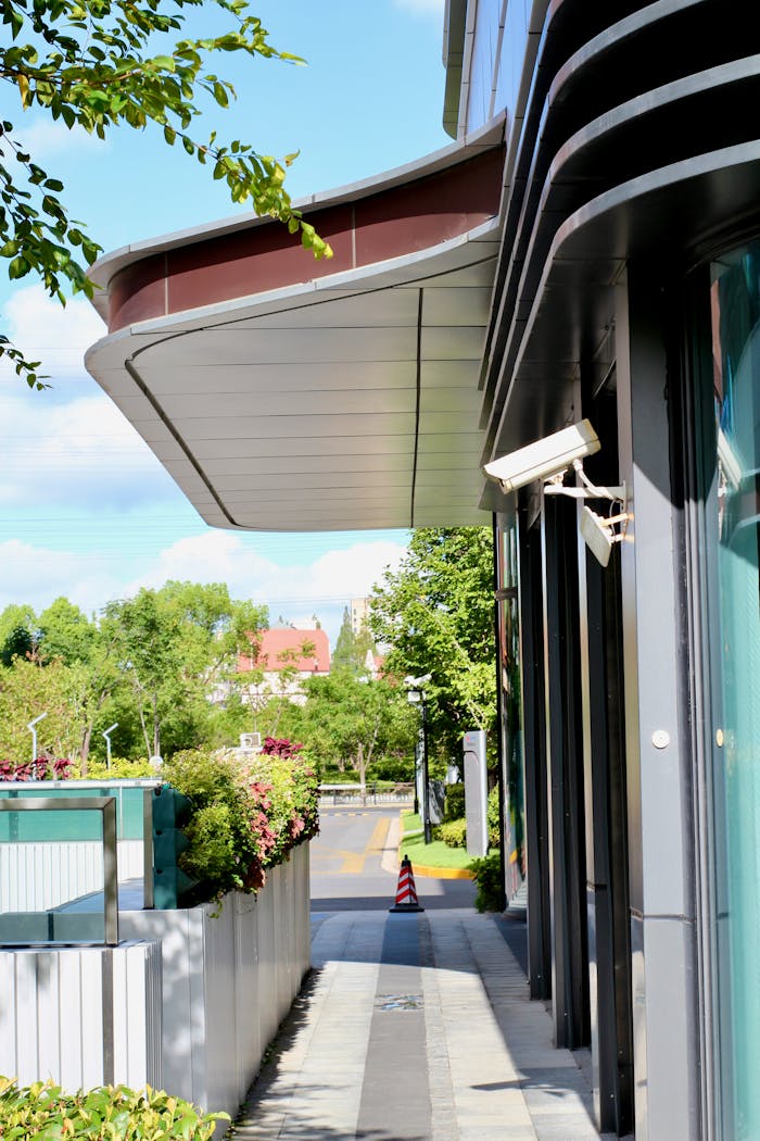 Street view of a modern building facade with CCTV in a sunny urban environment.
